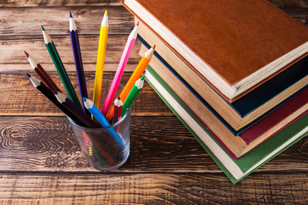 Books on the wooden table, colored pencils in glassの写真素材