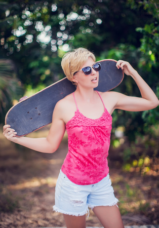 Beautiful young girl with skate board wearing sunglassesの写真素材