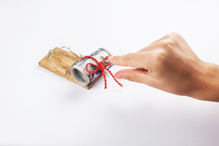 Money in a mousetrap with a hand. On a white background.