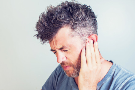 Man with earache is holding his aching ear body pain conceptの写真素材