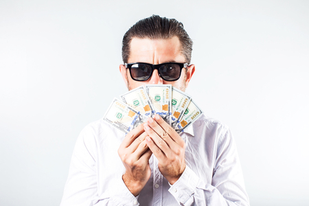 Bearded business man in shirt holding money and looking at the camera over white backgroundの写真素材