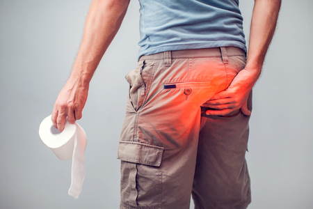 Man suffers from diarrhea holds toilet paper roll. The guy is holding the ass of himself trying to hold back the urgeの写真素材
