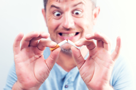 Cigarette being broken in two pieces by man stop smoking stop addictionの写真素材