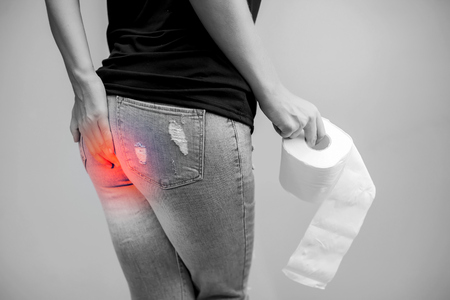 Woman suffers from diarrhea holds toilet paper roll. Stomach upset. Healthcare conceptの写真素材