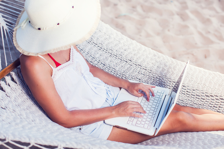 Woman using her laptop in hammock on the beachの写真素材