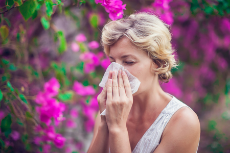 Woman with with allergy symptom blowing noseの写真素材