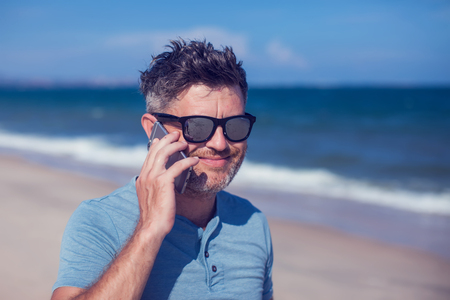 Young man using smartphone on the beachの写真素材