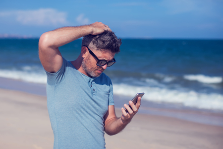 Young man using smartphone on the beachの写真素材