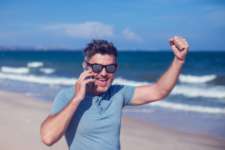 Young man using smartphone on the beachの写真素材