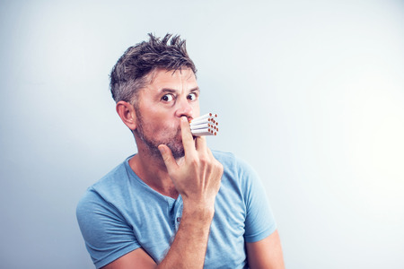 Young man with many cigarettes in his mouthの写真素材