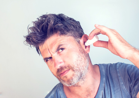 man using ear drops on gray backgroundの写真素材