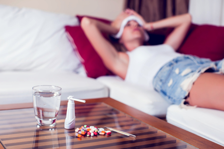 Sick woman lying in bed with high fever. Cold flu and migraine. Medicine and healthcare conceptの写真素材
