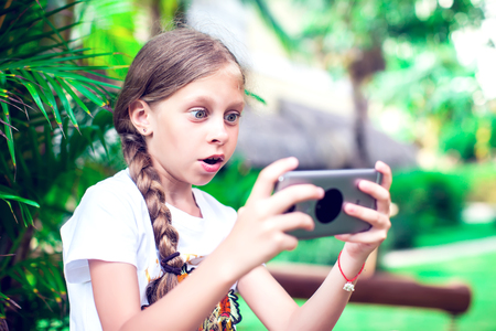 Technology and people concept - happy smiling girl using smartphone outdoorsの写真素材