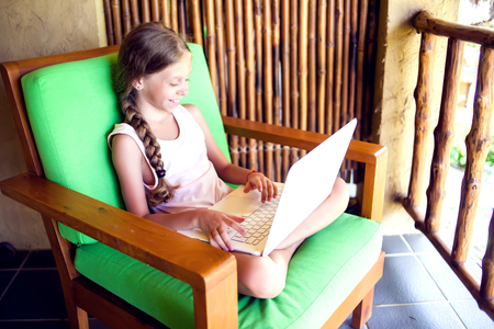 Technology, gaming and people concept - girl using laptop computer at homeの写真素材