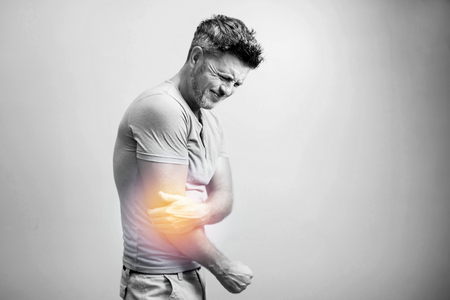 People, healthcare and problem concept - close up of man suffering from pain in hand or elbowの写真素材
