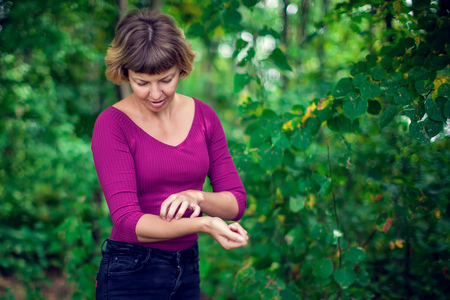 Health problem, skin diseases. Young woman with short hair scratching her itchy arm outdoor. Insect bitesの写真素材