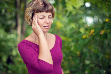 Young blonde short hair woman having serious migrene suffering from horrible head ache feeling big pain outdoor. Healthcare, medicine and people conceptの写真素材