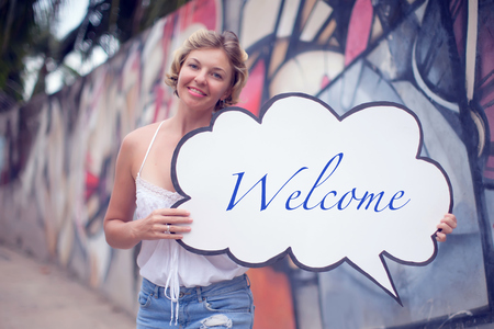 Young woman holding a speech bubble on a colorfull backgroundの写真素材