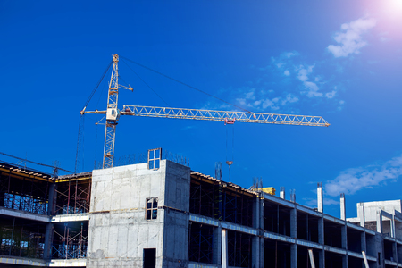 Construction crane on a building site against blue sky background.の写真素材