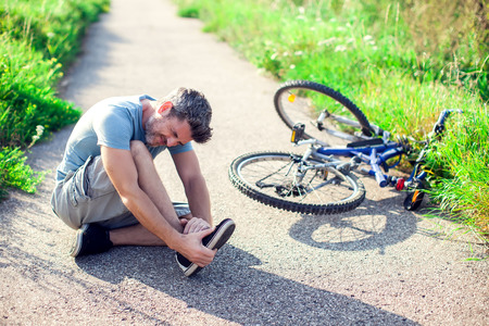 Man with dark hair with pain in knee joints after biking on bicycle. Sport, healthcare and people conceptの写真素材