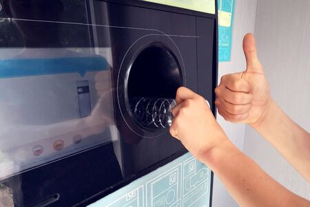 Man returns bottles and cans of reusable packagings in reverse vending machine. Environmental...