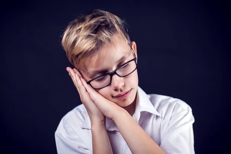 Tired boy teenager shows sleeping gesture. People and emotion conceptの写真素材