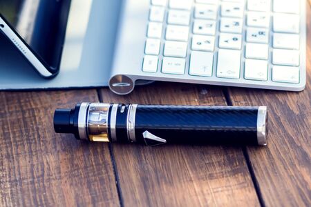 A vaporizer and laptop are on the wooden table. Smoke devise. Lifestyle conceptの写真素材