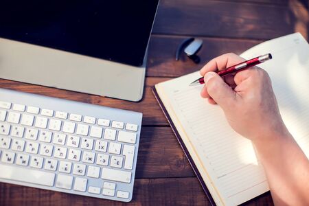 Businessman works with laptop and make records in notebook outdoor