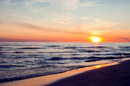 A sunset on the beach in summer. Sea and eveninig sky with cloudsの写真素材