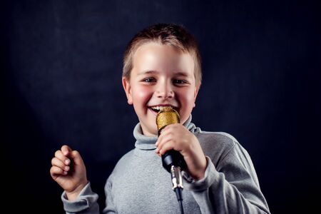 A portrait of a boy with microphone in front of dark background. Children, talent and entertainment conceptの写真素材
