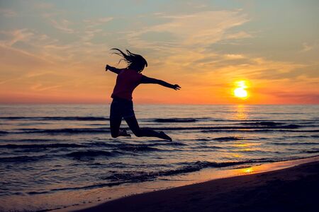 A silhuette of young woman relaxing on the beach in the eveninig. People and holiday conceptの写真素材