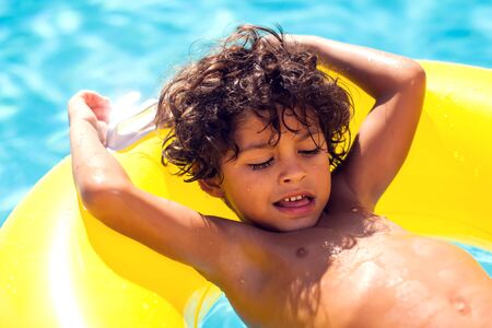Kid boy swims and has fun with inflatable circle in the pool. Children, summer and holiday concept