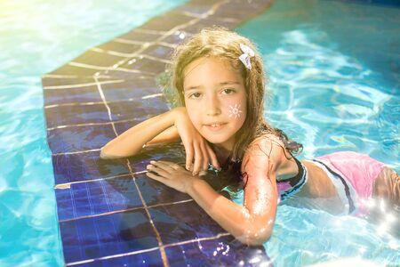 Kid girl with sun protection cream on her skin spends time in the pool. Children, summer, holiday...
