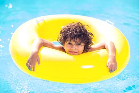 Kid boy swims and has fun with inflatable circle in the pool. Children, summer and holiday concept