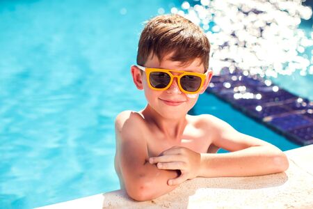 Kid boy with sun protection cream on his skin spends time  in the pool. Children, summer, holiday...