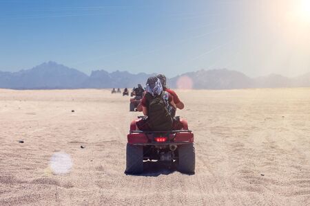 A group of quad bikes drive in the desert.の写真素材