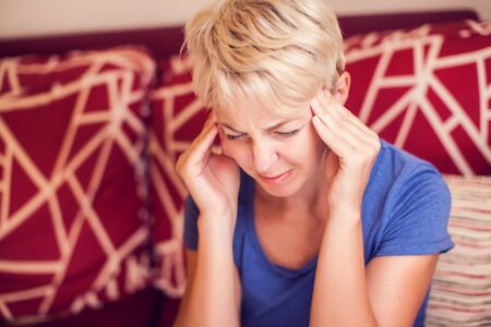 Woman feels strong headache at home. People, healthcare and medicine conceptの写真素材