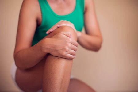 Woman with short hair feels strong knee pain isolated. People, healthcare and medicine conceptの写真素材