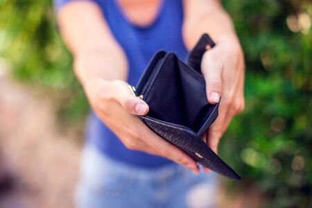 Woman holds an empty wallet in hands outdoor. Finance problem conceptの写真素材