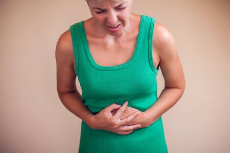Woman with short hair feels strong stomach pain isolated. People, healthcare and medicine concept