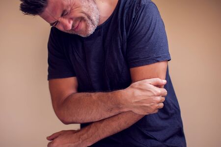 Man feels strong pain in elbow isolated. People, healthcare and medicine conceptの写真素材