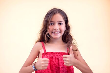 Little girl shows thumbs up sign and smile. Children and emotions concept.の写真素材