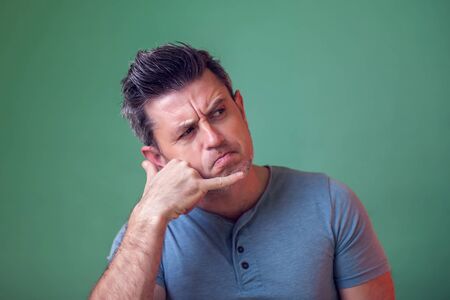 Portrait of serious handsome young man making a call me sign. People, emotions and lifestyle concept.の写真素材
