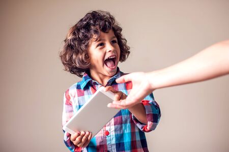 Computer addiction, parent taking out touch pad from childの写真素材