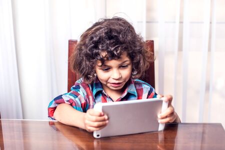 Little boy looking at touch pad at home. Children and technology concept