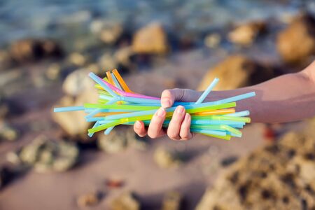 Close Up Of HandsHolding Plastic Straws Polluting Beach. Environmental pollution conceptの写真素材