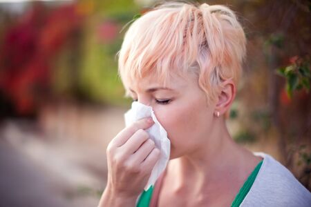 Woman with with allergy symptom blowing nose. Health care and medical conceptの写真素材