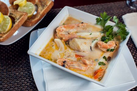 Seafood cream soup with toasts in white plate on the table.の写真素材