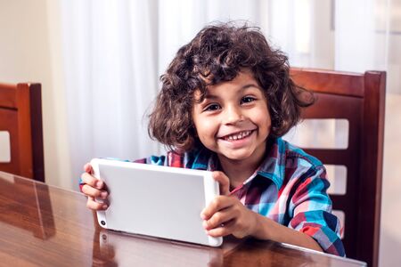 Little boy looking at touch pad at home. Children and technology conceptの写真素材