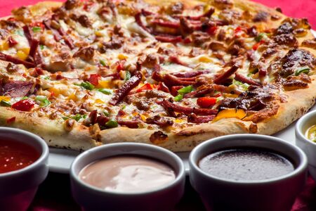 Delicious pizza with with sauces on the table in cafe. Food conceptの写真素材